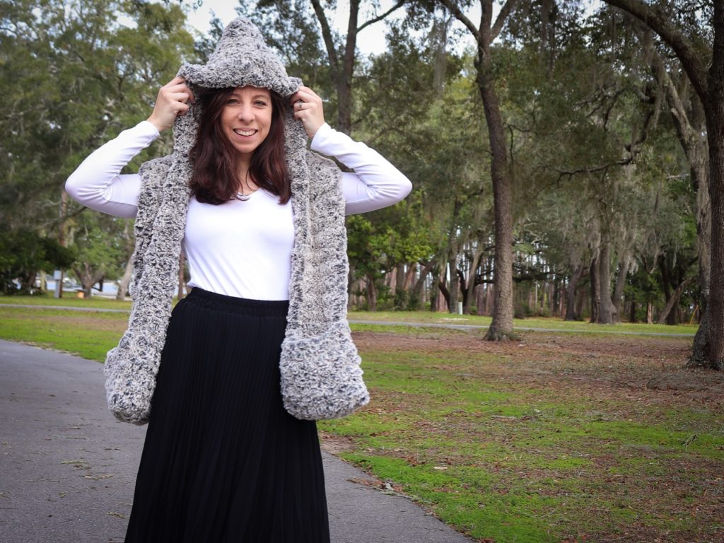 Sigoni is modeling the finished Faux Fur Hooded Scarf with Pockets in a wooded park