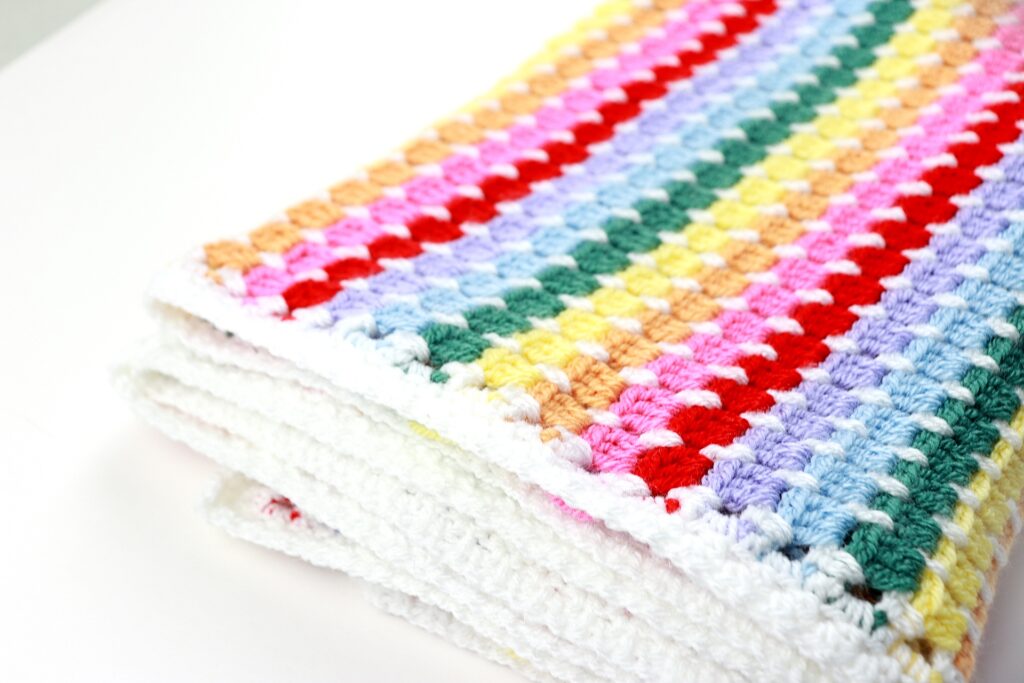 Folded finished Rainbow Baby Blanket crochet pattern after weaving in ends