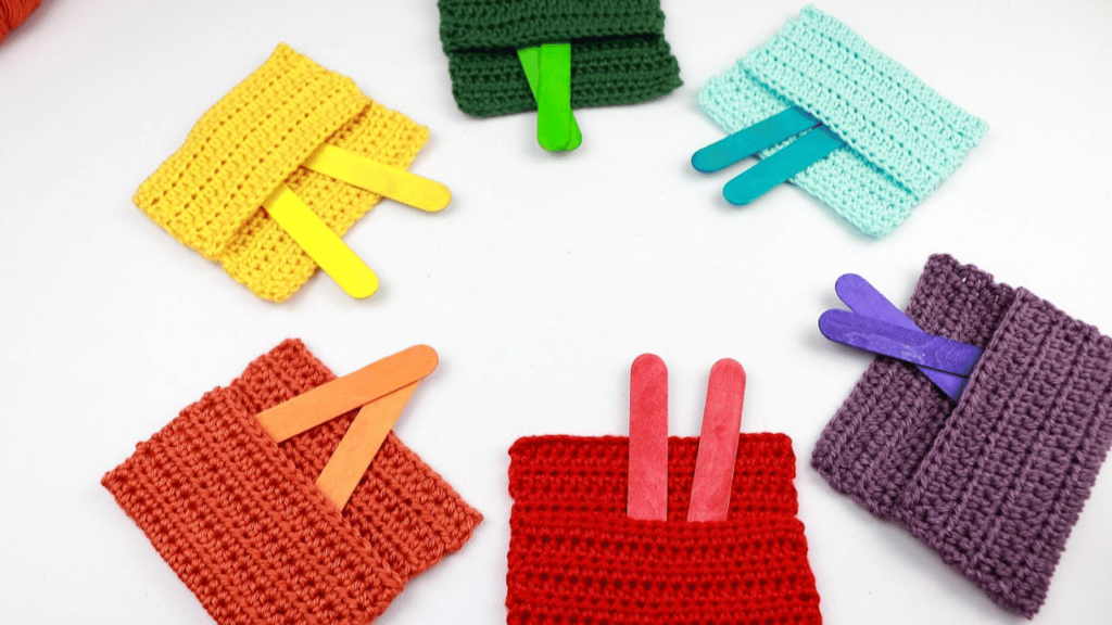 Six Crochet Color Pockets (a quick easy crochet toy for babies) in the colors red, orange, yellow, green, blue, and purple. Each pocket has two colorful popsicle sticks to match.