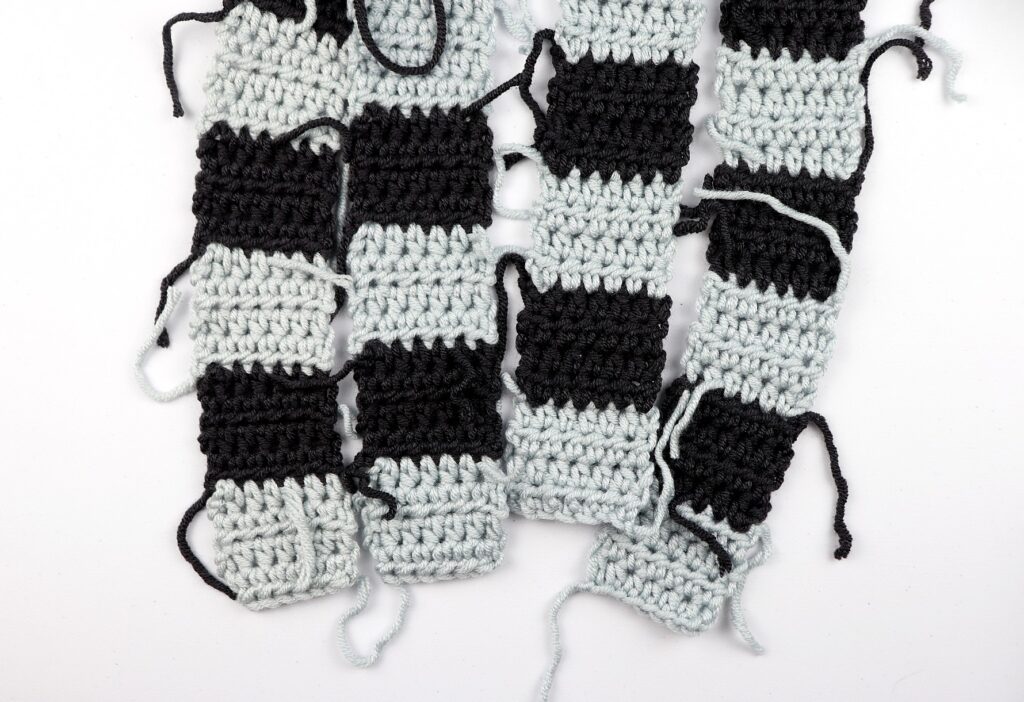 4 half double crochet panels in two colors (grey and black) of the simple gingham style crochet pillow cover.