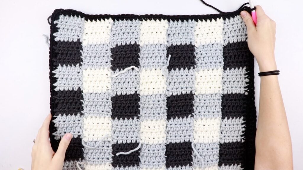 front side of the gingham style crochet pillow cover in traditional gingham colors (black grey white)