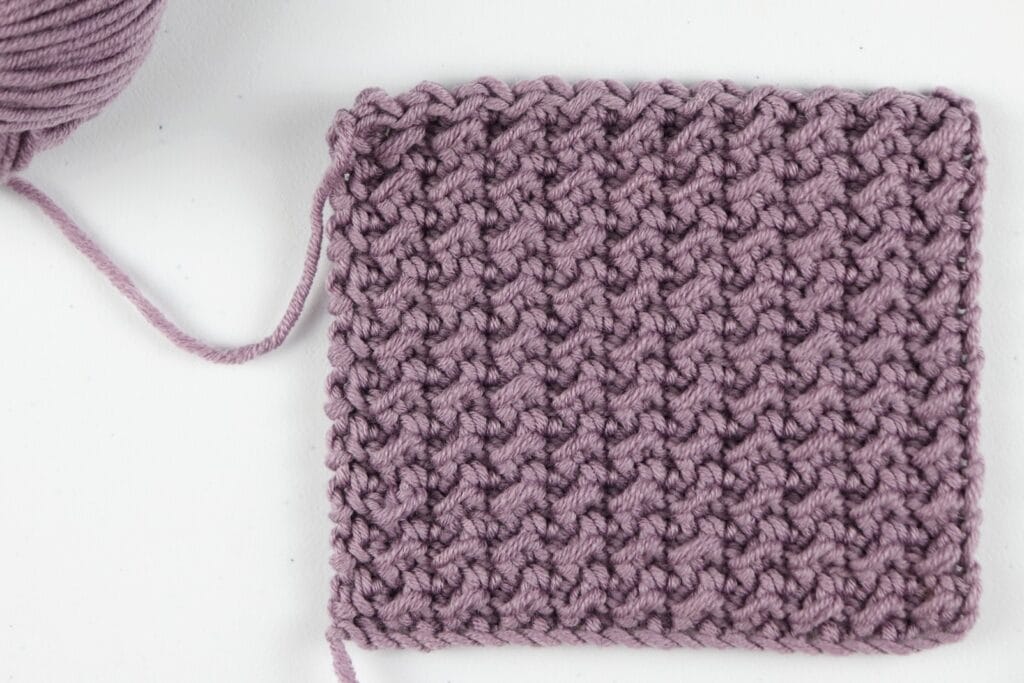 The finished Crunch Stitch swatch sample in the color purple using Milla Mia yarn.