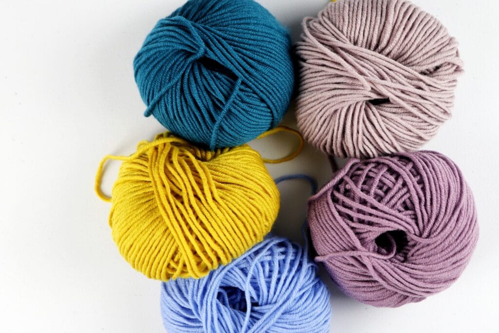 Milla Mia yarn in the colors purple, dark blue, yellow, tan, and light blue