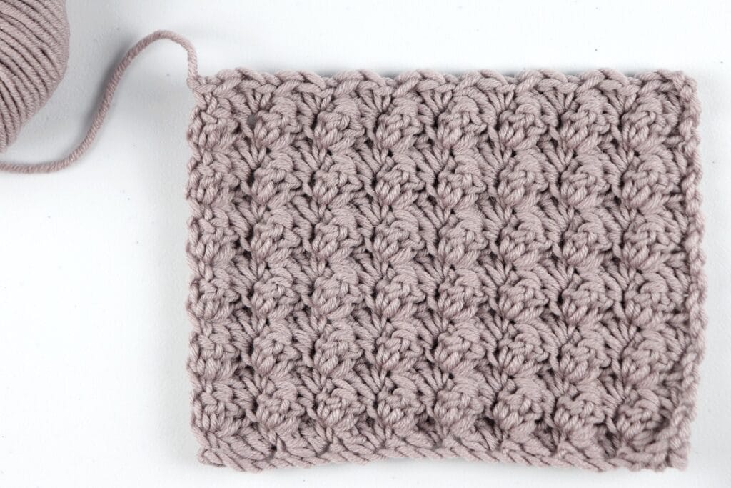 The finished Blanket Stitch swatch sample in the color purple using Milla Mia yarn. 