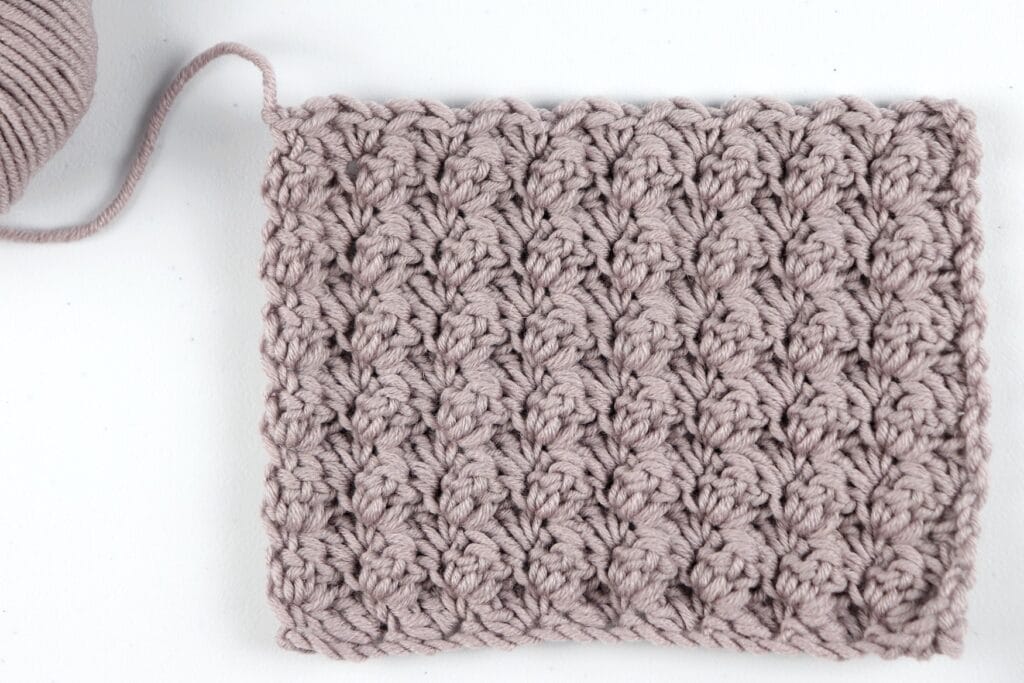 The finished Blanket Stitch swatch sample in the color purple using Milla Mia yarn.